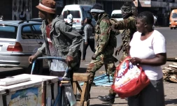 Deux soldats zimbabwéens cagoulés crient des ordres à des vendeurs de rue et des changeurs de billets, lors d'une patrouille dans les rues de Harare, le 2 août 2018
