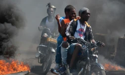 Des hommes à moto passent entre des pneus en feu lors d'une manifestation aprÚs l'annonce de la démission du Premier ministre Ariel Henry, à Port-au-Prince en Haïti, le 12 mares 2024