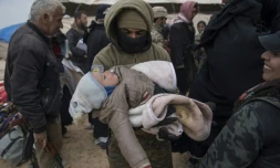Un membre des Forces démocratiques syriennes (FDS) porte dans ses bras un enfant qui a fui avec sa famille le groupe Etat islamique à Baghouz, le 14 février 2019