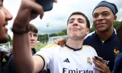 L'attaquant français Kylian Mbappé prend un selfie avec un fan portant un maillot du Real Madrid, le 30 mai 2024 à Clairefontaine-en-Yvelines