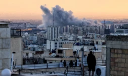 Des personnes sur le toit d'un immeuble observent un panache de fumée après une frappe sur Téhéran, le 3 mars 2026 en Iran