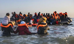 Des migrants avancent dans l'eau pour embarquer sur le bateau d'un passeur et tenter de traverser la Manche au large de la plage de Gravelines, le 16 juin 2025 dans le Nord