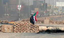 Un manifestant portant un drapeau soudanais passe devant des barrages routiers érigés par des manifestants dans une rue de la capitale Khartoum, le 26 octobre 2021