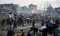 Des Palestiniens marchent le long d'une route de retour d'un point de distribution d'aide de la Fondation humanitaire de Gaza (GHF,) près du camp de réfugiés de Nousseirat, dans le centre de la bande de Gaza, le 25 juin 2025