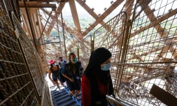 Des visiteurs portant des masques de protection montent les escaliers de la Tour Eiffel, le jour de sa réouverture, le 25 juin 2020 à Paris 