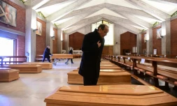 Le prêtre de la paroisse de Seriate, Don Mario, s'incline devant l'un des cercueils entreprosés dans l'église de sa commune, située près de Bergame, dans le nord de l'Italie, le 26 mars 2020