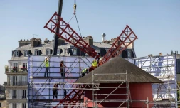 Des ouvriers installent l'une des quatre pales provisoires au sommet du cabaret le Moulin Rouge, après l'effondrement des anciennes ailes, le 24 juin 2024 à Paris