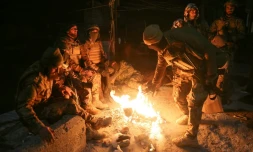 Des combattants antigouvernementaux se réchauffent autour d'un feu dans le centre d'Alep, le 30 novembre 2024
