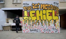 Un policier à côté d'un graffiti indiquant "Par ici mes abeilles, vous trouverez du miel ouvert 10/2h 7j/7" ,dans un point de dealer connu dans les quartiers nord de Marseille, le 1er décembre 2023