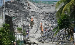 Des militaires accompagnés d'un chien fouillent les décombres d'un immeuble effondré à Angeles City, dans la province de Pampanga, au nord de Manille, le 25 mai 2026 aux Philippines