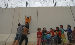 Des enfants déplacés syriens
tentent d'escalader le mur de la frontière turque, dans la province d'Idleb, le 21 février 2020