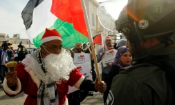 Un manifestant palestinien habillé en pÚre Noël s'oppose à un membre des forces de l'ordre israélienne à Bethléem, en Cisjordanie occupée, le 23 décembre 2017