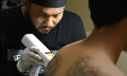 Sandi Widodo  travaille sur un client musulman qui souhaite effacer ses tatouages, le 18 avril 2018 à Jakarta, en Indonésie