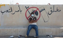 Un manifestant se repose prĂšs d'un muret oĂč un slogan antigouvernemental a Ă©tĂ© inscrit, Ă Oum Qasr, dans le sud de l'Irak, le 3 novembre 2019