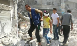 Des Syriens marchent sur des décombres après des raids aériens sur le quartier Fardous de Alep, le 12 octobre 2016.