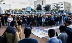 Des personnes autour d'une pancarte commémorant le nom des huit migrants décédés en tentant de traverser la Manche, à Calais, le 16 septembre 2024