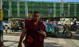 Un moine bouddhiste marche près d'un immeuble en reconstruction le 1er juin 2021 à Lhassa dans la région autonome du Tibet