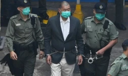 Jimmy Lai (c) est escorté par des policiers dans un véhicule de police pour se rendre au tribunal, à Hong Kong, le 12 décembre 2020