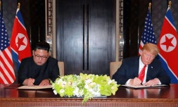 Le président américain Donald Trump et le dirigeant nord-coréen Kim Jong Un signent des documents lors de leur sommet à Singapour, sur une photographie prise le 12 juin 2018 et diffusée le lendemain par l'agence officielle nord-coréenne KCNA