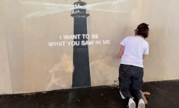 Agnès Perrone, peintre en décor du patrimoine, répare une œuvre d'art de l'artiste de rue Banksy représentant un phare sur la façade d'un bâtiment, après qu'elle a été vandalisée pendant la nuit à Marseille, le 1er juin 2025