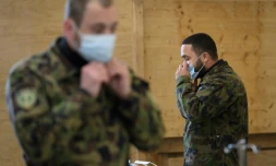 Deux militaires de l'armée suisse enfilent un masque de protection lors d'une formation à Bière (ouest) le 22 mars 2020