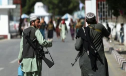 Deux combattants talibans se dirigent vers l'entrée principale de l'aéroport de Kaboul, le 28 août 2021