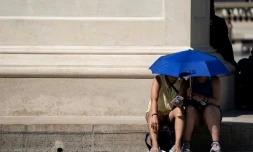 Des personnes se protègent du soleil près de la Pyramide du Louvre, à Paris le 26 juin 2019
