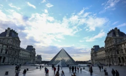 Des touristes prÚs de la pyramide du Louvre, conçue par l'architecte sino-américain Ieoh Ming Pei, le 28 février 2025