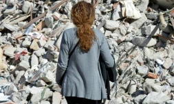 Une femme devant les décombres d'un immeuble détruit par le séisme à Amatrice, le 26 août 2016