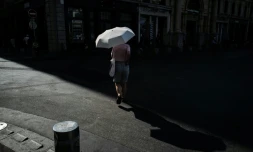 Une femme marche sous un parapluie pour se protéger du soleil lors d'une vague de chaleur à Lyon, dans le Rhône, le 24 juin 2026