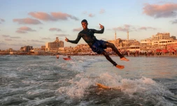 Un jeune Palestinien surfe au large d'une une plage de la ville de Gaza, le 21 juin 2026
