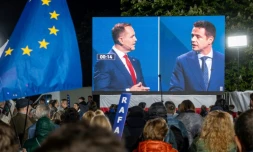 Des partisans du maire de Varsovie pro-européen, Rafal Trzaskowski (d), observent un débat entre leur candidat et son principal adversaire à la présidentielle, le nationaliste Karol Nawrocki (g), à Varsovie, le 12 mai 2025