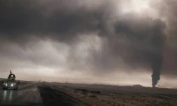 Un véhicule de l'armée irakienne emprunte une route près de Mossoul, sous la fumée d'un puits de pétrole enflammé par l'EI, le 4 novembre 2016.