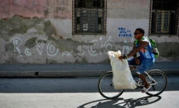 Un homme passe en vélo devant un graffiti "Revolucion" à Santiago de Cuba, le 31 décembre 2018