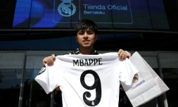 Un supporteur pose avec un maillot du Real floqué Kylian Mbappé, devant une boutique du club, le 11 juillet 2024 à Madrid