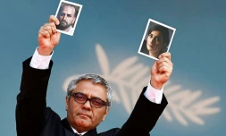 Le réalisateur iranien Mohammad Rasoulof brandit les photos de l'acteur iranien Missagh Zareh, à gauche, et de l'actrice iranienne Soheila Golestani, à droite, le 24 mai 2024, au festival de Cannes, dans les Alpes-Maritimes