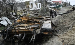 Des habitants passent près d'un tank russe détruit dans le village de Zalissya (Ukraine), au nord-est de Kiev, le 19 avril 2022