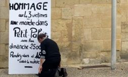 Un homme s'agenouille devant l'affiche appellant à un hommage aux victimes de la collision de Puisseguin le 24 octobre 2015 à Petit-Palais