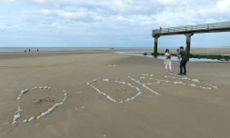 Une famille sur "Omaha Beach", où le mot "D-Day" a été tracé à l'aide de galets, à  Vierville-sur-Mer, dans le Calvados, lors des célébrations du 75e anniversaire du Débarquement en juin 2019