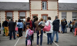 Des enfants et leurs parents devant une école primaire