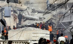 Des Syriens et des membres des forces de sécurité devant un bùtiment détruit par une frappe à Damas attribuée à Israël, le 20 janvier 2024