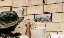 Un membre des Forces démocratiques syriennes (FDS) montre la position des snipers du groupe jihadiste Etat islamique (EI)