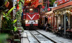 Un train passe au ras des cafés et des habitations dans la célèbre et touristique "rue du train" à Hanoi, le 18 août 2025 