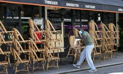 Un employé nettoie les chaises avant la réouverture des terrasses des cafés, bars et restaurants, le 30 mai 2020 à Paris
