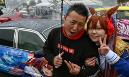 Yosuke Takahata (g) et une jeune femme en costume de l'héroïne d'animation Daïwa Scarlet devant une voiture personnalisée, pendant le festival "Itasha Tengoku", le 26 mars 2023 à Tokyo