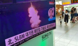 Une personne passe devant un écran de télévision à Séoul le 25 août 2016 sur lequel sont diffusées les images d'un tir de missile