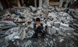 Un enfant mange dans les décombres d'un immeuble détruit par une frappe israélienne, le 29 décembre 2023 à Rafah, dans le sud de la bande de Gaza