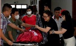 Des proches réunis autour du corps d'une victime du naufrage d'un bateau de tourisme dans la baie d'Halong, le 20 juillet 2025 à Halong au Vietnam