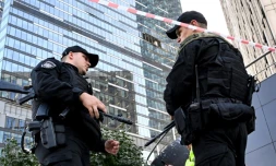 Deux agents de police bouclent le périmÚtre autour d'un immeuble de bureaux endommagé de Moscou City aprÚs une attaque de drone rapportée par la Russie, le 1er août 2023 à Moscou