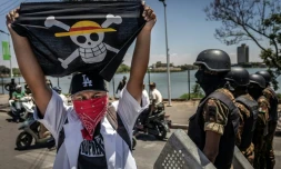 Un drapeau portant le logo du célèbre manga japonais One Piece, symbole adopté par les mouvements de protestation de la génération Z dans le monde entier, devant les forces de sécurité lors d'une manifestation exigeant de meilleures conditions de santé et des réformes constitutionnelles à Antananarivo, le 7 octobre 2025 à Madagascar